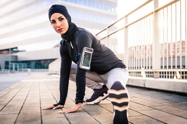 Ragazza sportiva musulmana con allenamento del corpo in forma all'esterno