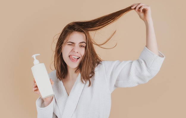 Ragazza stupita sorpresa che applica balsamo per capelli Giovane donna che applica maschera per capelli