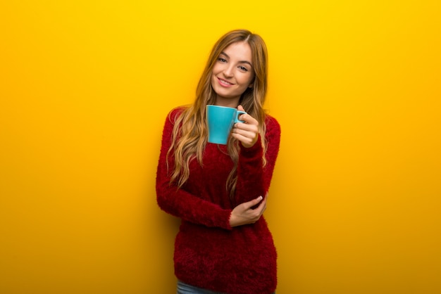 Ragazza su giallo vibrante che tiene una tazza di caffè calda