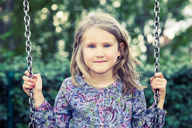 Ragazza su oscillazione nel parco estivo