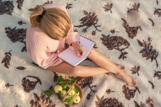 Ragazza su un picnic sulla natura riposa su una coperta di coperte