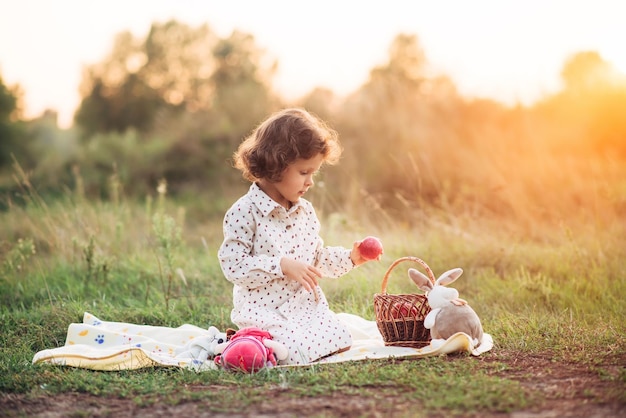 ragazza su un prato alla luce del sole al tramonto. tiene in mano mele mature. Infanzia spensierata