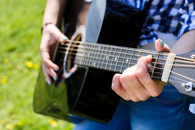 Ragazza su un prato verde a suonare la chitarra