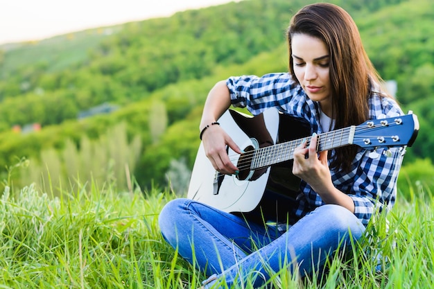 Ragazza su un prato verde a suonare la chitarra