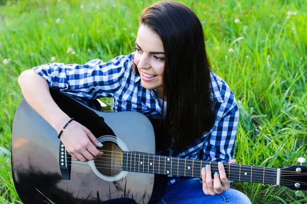 Ragazza su un prato verde a suonare la chitarra