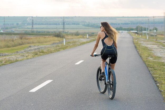 Ragazza su una mountain bike in fuoristrada bellissimo ritratto di un ciclista al tramonto