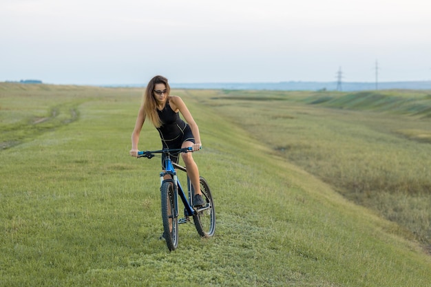 Ragazza su una mountain bike su fuoristrada bellissimo ritratto di un ciclista al tramonto Ragazza fitness cavalca una moderna mountain bike in fibra di carbonio in abbigliamento sportivo