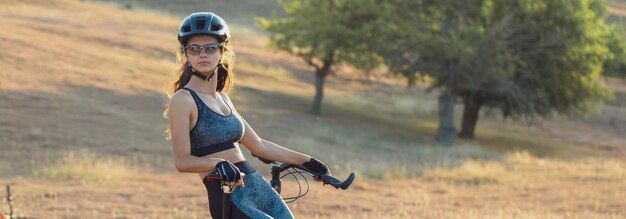 Ragazza su una mountain bike su fuoristrada bellissimo ritratto di un ciclista al tramonto Ragazza fitness cavalca una moderna mountain bike in fibra di carbonio in abbigliamento sportivo