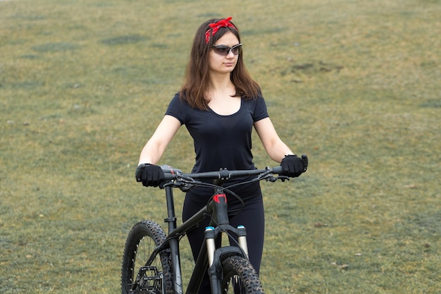 Ragazza su una mountain bike su fuoristrada bellissimo ritratto di un ciclista al tramonto Ragazza fitness guida una moderna mountain bike in fibra di carbonio in abbigliamento sportivo Ritratto del primo piano di una ragazza con casco e occhiali