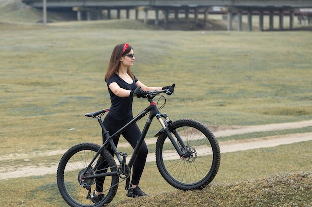 Ragazza su una mountain bike su fuoristrada bellissimo ritratto di un ciclista al tramonto