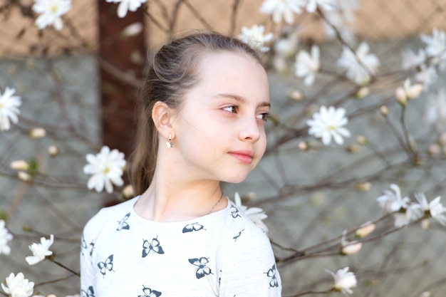 Ragazza sul fiore floreale in primavera. Ragazza con fiori che sbocciano all'aperto.