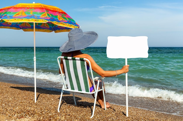 Ragazza sulla spiaggia che prende il sole ragazza con un computer portatile donna sotto un ombrellone sedia ombrellone piatto resto o