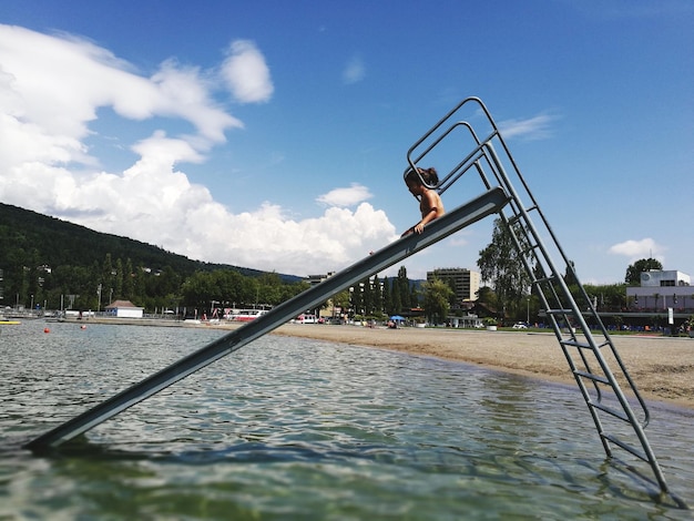 Ragazza sullo scivolo d'acqua contro il cielo