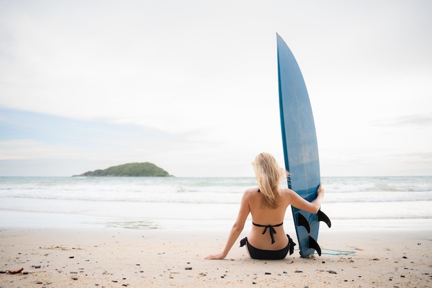 Ragazza surfista con la sua tavola da surf sulla spiaggia
