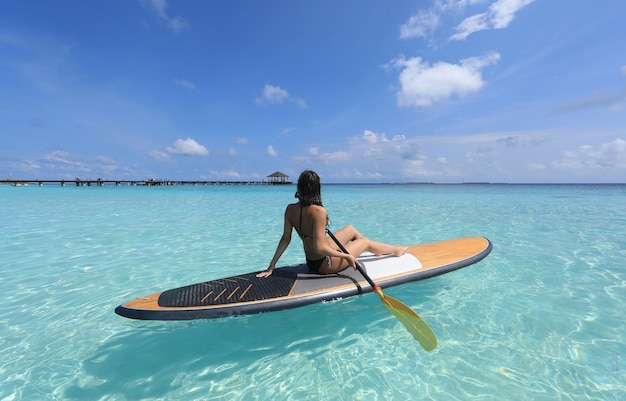 Ragazza surfista SUP alle Maldive