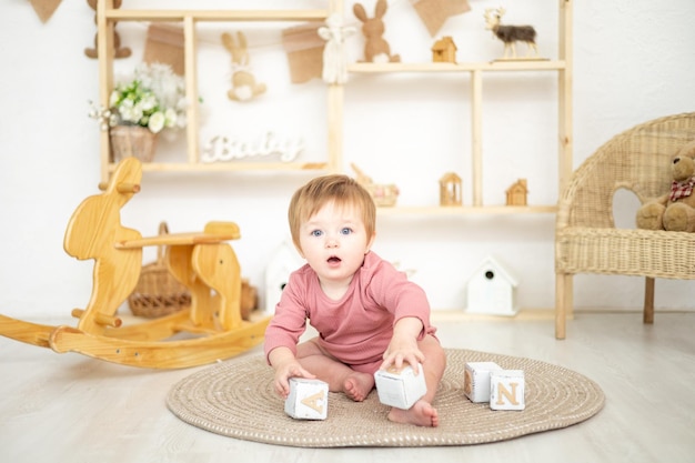 Ragazza sveglia che gioca con i giocattoli naturali di legno nella stanza dei bambini a casa giocattoli educativi per l'interno della stanza dei bambini dei bambini