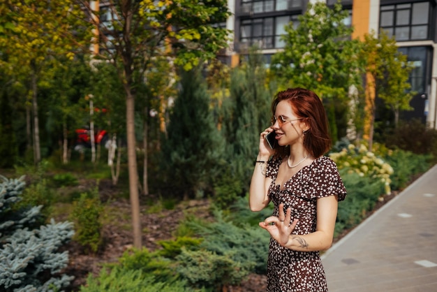 Ragazza sveglia che parla sul telefono cellulare sullo sfondo della città moderna