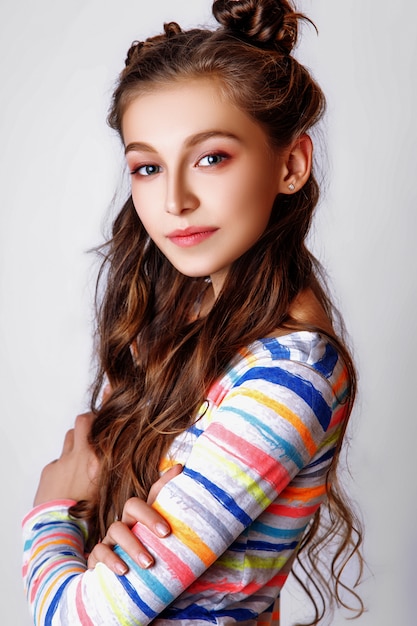 Ragazza sveglia con capelli ricci lunghi che posano studio