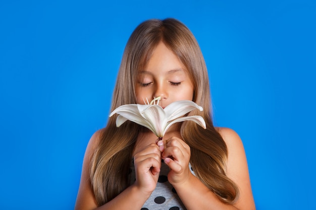 Ragazza sveglia con gli occhi chiusi che odorano un fiore