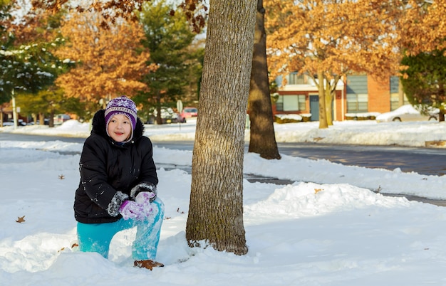 Ragazza sveglia del bambino in snowsuit caldo che gioca con una neve.