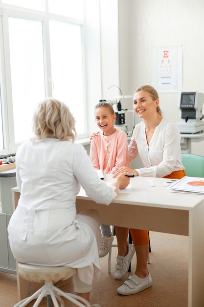 Ragazza sveglia di risata che sta bene nell'armadietto medico