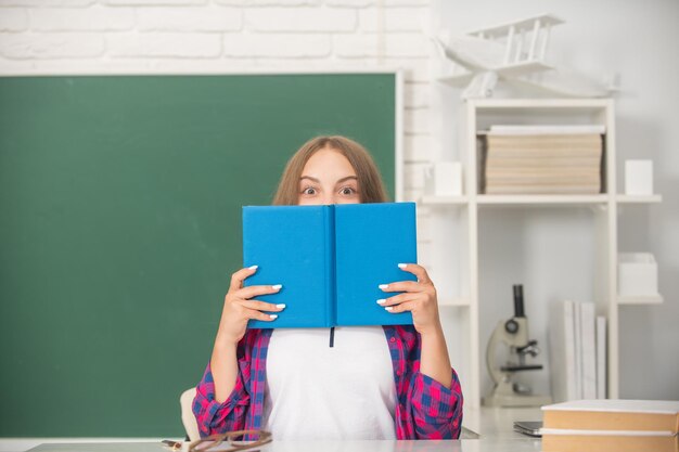 Ragazza teenager al liceo dietro la cartella di lavoro all'erudizione della lavagna