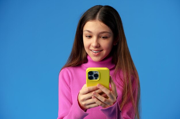Ragazza teenager alla moda che utilizza smartphone su sfondo blu