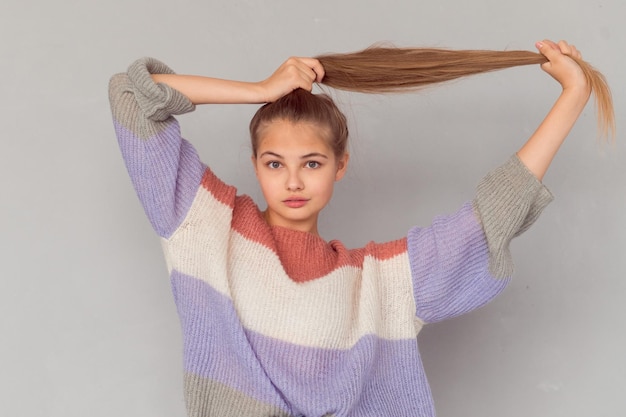 Ragazza teenager allegra che tiene la coda che guarda l'obbiettivo e sorridente