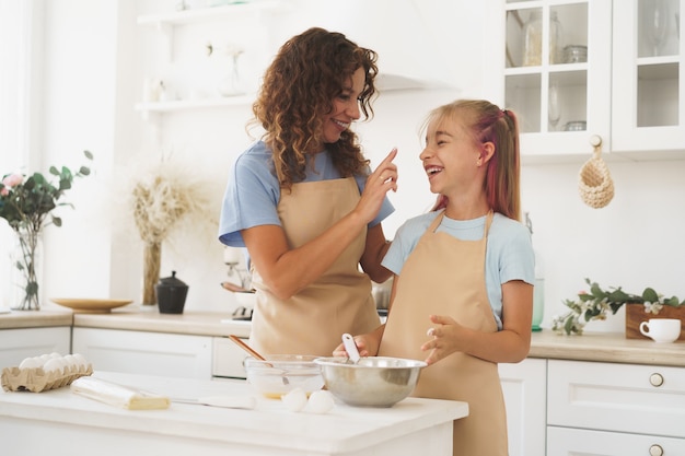 Ragazza teenager che aiuta sua madre a cucinare la pasta nella loro cucina a casa