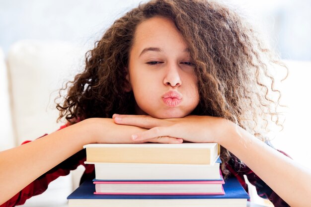 Ragazza teenager che riposa sui libri nella stanza