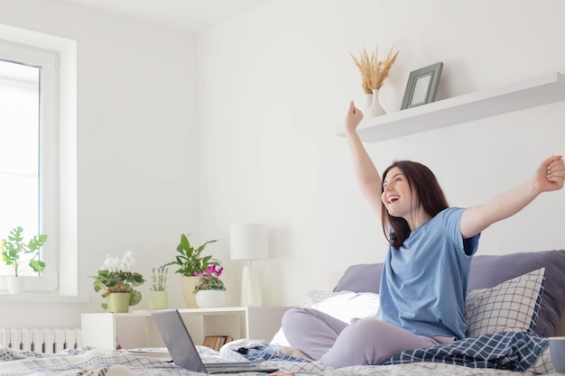 Ragazza teenager che studia a casa sul letto con il computer portatile