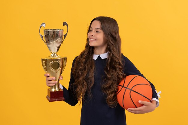 Ragazza teenager del premio al successo sportivo con palla da basket e coppa del campione