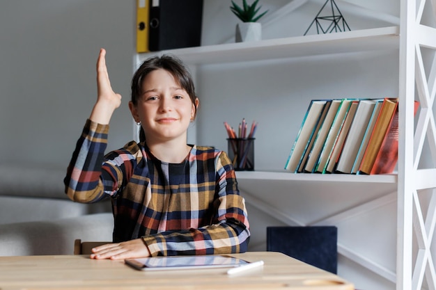 Ragazza teenager dell'allievo che studia e che alza la mano a scuola