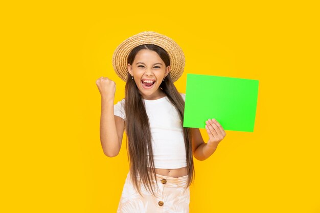 Ragazza teenager di successo con lo spazio della copia su carta verde su fondo giallo