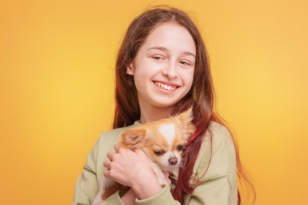 Ragazza teenager in una giacca verde con un cane di razza Chihuahua su sfondo giallo Ragazza e cane bianco