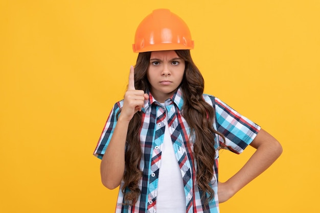 Ragazza teenager rigorosa con capelli ricci in casco da costruzione, esperto.