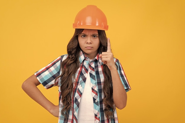 Ragazza teenager rigorosa con i capelli ricci nell'esperto del casco della costruzione