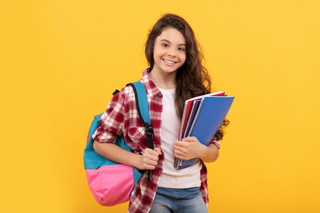 Ragazza teenager sorridente della scuola pronta a studiare con l'istruzione dello zaino e dei quaderni