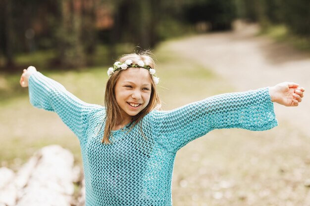 Ragazza teenager sorridente sveglia che si rilassa e che gode nella natura alla giornata di sole primaverile.