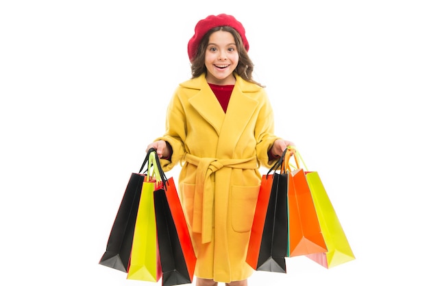 Ragazza tenere borse della spesa Modello con capelli lunghi su sfondo bianco Bambino portare regali in sacchetti di carta Piccolo maniaco dello shopping con borse della spesa Tendenza della moda e concetto di vendita Shopping online