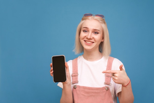 ragazza tiene uno smartphone con uno schermo nero, mostra un dito sullo schermo