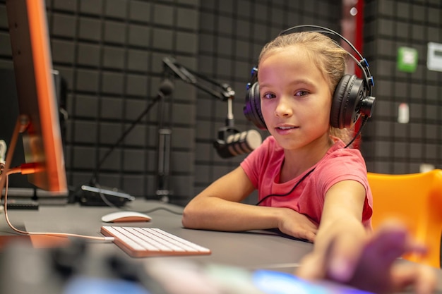 Ragazza tranquilla concentrata che si siede nello studio di radiodiffusione