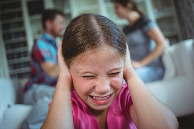 Ragazza triste che ascolta la discussione dei suoi genitori