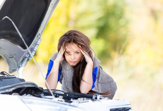 Ragazza triste con bei capelli alla macchina rotta