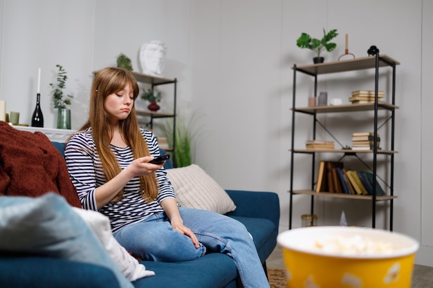 Ragazza triste con telecomando TV sul divano