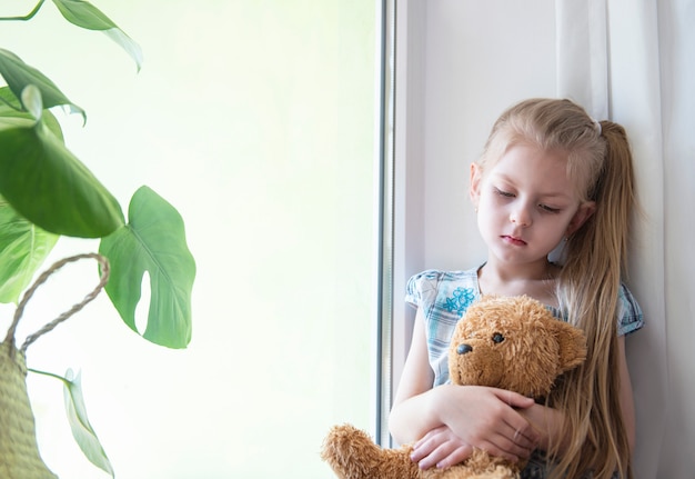 Ragazza triste del bambino vicino alla finestra