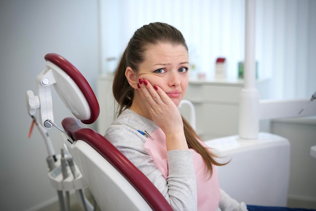 Ragazza triste e frustrata giovane donna sta piangendo tenendo la guancia soffrendo di forti denti dolore in bocca