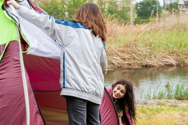 Ragazza troppo giovane che monta la tenda al campeggio