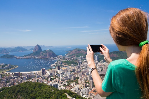 Ragazza turista scatta una foto del paesaggio di Rio con lo smartphone