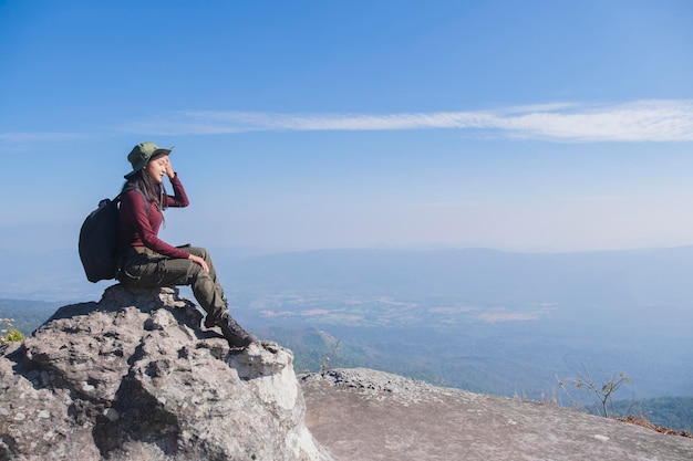 Ragazza turistica che si siede sulla pietra alla montagna che osserva vista panoramica